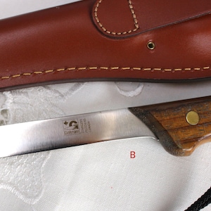 May include: A close-up of a silver knife with a wooden handle. The knife has a Canadian flag and the text "STAINLESS  RIGIDUNS  CANADA" on the blade.