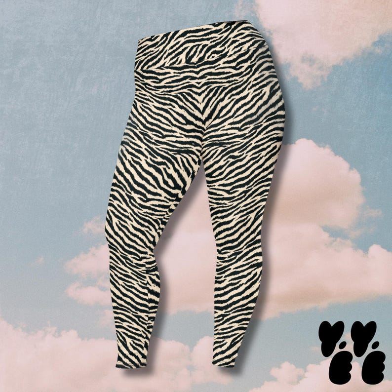 May include: High-waisted leggings featuring a black and cream zebra stripe pattern. The garment has a fitted silhouette that extends from the waist down to the ankles, showcasing a continuous animal print design across the entire fabric surface.