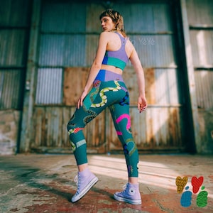 May include: A matching athletic set consisting of a racerback sports bra and high-waisted leggings. The fabric features a teal base with a multi-colored abstract pattern of wavy lines, dots, and shapes in pink, yellow, blue, and white.