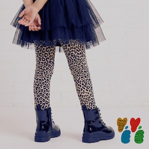May include: A navy blue tiered tulle skirt paired with leopard print leggings featuring a tan and black pattern. The outfit is completed with shiny navy blue lace-up boots. Four small heart-shaped icons in yellow, red, blue, and green are visible.