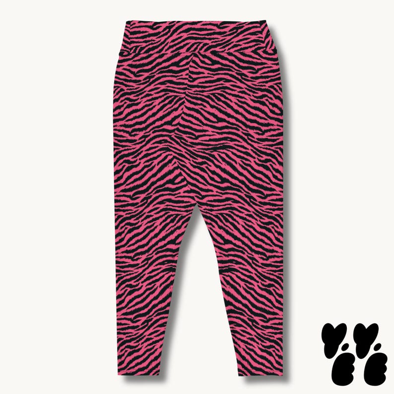 May include: High-waisted leggings featuring a vibrant hot pink and black zebra stripe pattern. The garment has a fitted silhouette with a wide waistband and tapered legs that extend down to the ankles, showcasing a bold animal print design.