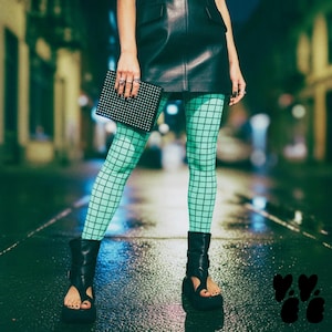 May include: A black leather mini skirt, mint green leggings with a black grid pattern, a black rectangular studded clutch, and black open-toe platform boots. The outfit features a high-contrast combination of textures and geometric patterns.