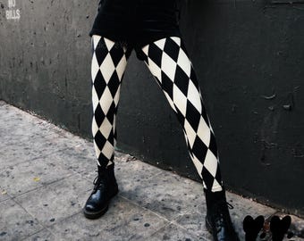 May include: Black and white harlequin patterned leggings paired with black velvet shorts, a pinstriped corset top with gold buttons, black leather gloves, and black lace-up combat boots. The leggings feature a repeating diamond pattern throughout.