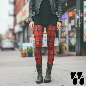 May include: Red tartan leggings featuring a classic plaid pattern with black and yellow intersecting lines. The leggings are worn with a black leather jacket and dark olive green lace-up combat boots that reach mid-calf with a rounded toe.