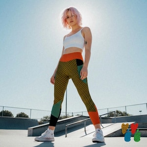 May include: A white cropped tank top paired with high-waisted leggings featuring a mustard yellow base with a black geometric pattern, solid orange waistband and cuffs, and solid sage green and black color-blocked panels on the lower legs.