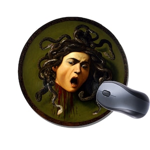 Può includere: Un tappetino per mouse rotondo con un dipinto di Medusa, una figura mitologica greca con capelli di serpente, su uno sfondo verde. Il dipinto è in una cornice circolare.