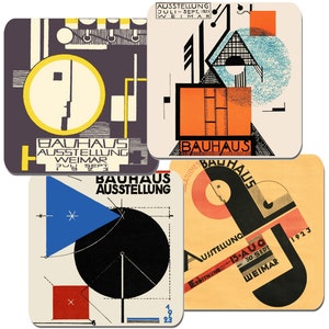 May include: A set of four square coasters displaying Bauhaus exhibition posters. The coasters feature geometric designs in black, yellow, red, and blue, with text detailing the exhibition. These coasters are designed to protect surfaces from spills and heat.