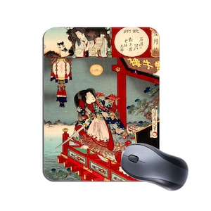 May include: Mouse mat with a Japanese woodblock print depicting a woman with a sword on a red bridge. The print includes a full moon, figures, and Japanese text. A grey wireless mouse is next to the mouse mat.