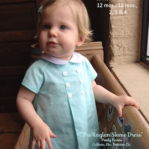 May include: A young child wearing a light blue dress with white buttons and a white collar. The dress has a raglan sleeve design. The text "The Raglan Sleeve Dress" is printed on the dress, along with the designer's name, "Trudy Horne", and the company name, "Collars, Etc. Pattern Co.".