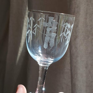 May include: A clear glass wine glass with an etched design of bamboo and Chinese characters. The glass has a short stem and a round base.