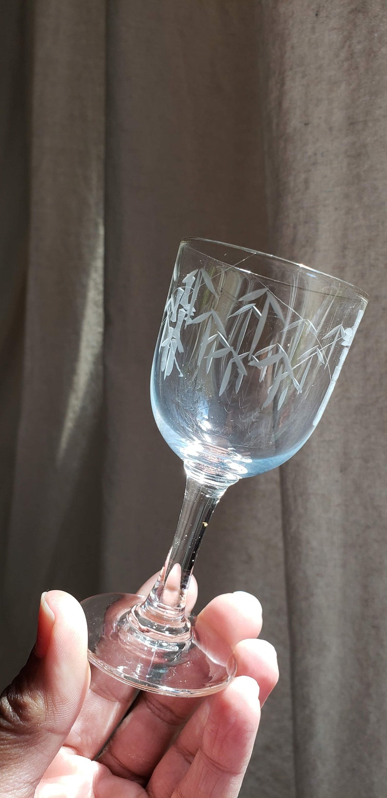 May include: A clear glass stemmed shot glass with an etched design of bamboo leaves.