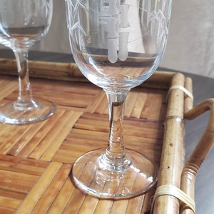 May include: Two clear glass shot glasses with etched bamboo designs on a bamboo tray. The glasses have a delicate stem and a round base.
