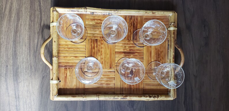 May include: A bamboo tray with six clear glass cups. The tray has a woven pattern and two handles.