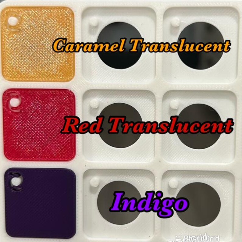 May include: A close-up of a white tray with nine compartments, each containing a small, square, translucent sample. The samples are caramel, red, and indigo. Text on the image reads "Caramel Translucent", "Red Translucent", and "Indigo".