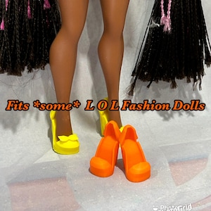 May include: A pair of bright orange doll heels and a pair of yellow doll shoes with bows. The text "Fits *some* LOL Fashion Dolls" is displayed in the image.