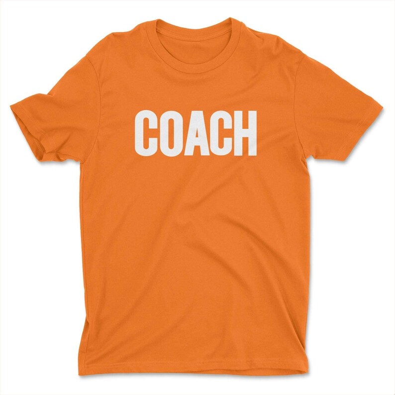 K&ouml;nnte beinhalten: Orangefarbenes T-Shirt mit dem Wort "COACH" in wei&szlig; auf der Vorderseite.