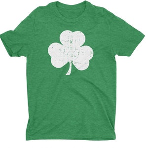 Pode incluir: Uma camiseta verde com um design de trevo branco desbotado.