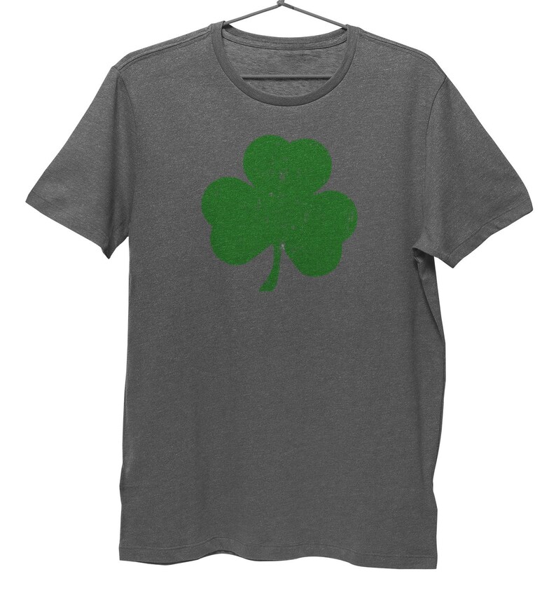Pode incluir: Uma camiseta cinza mescla com um gr&aacute;fico de trevo verde.