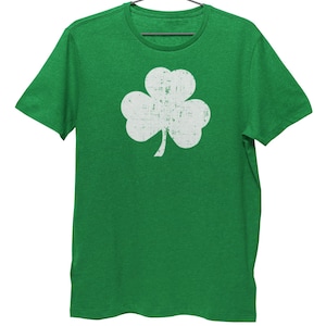 Pode incluir: Uma camiseta verde com um design de trevo branco desbotado.