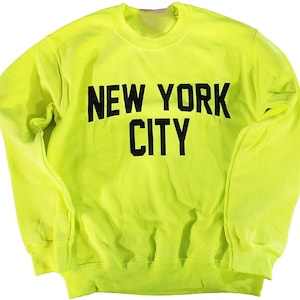 May include: A bright yellow sweatshirt with black text that reads "NEW YORK CITY".