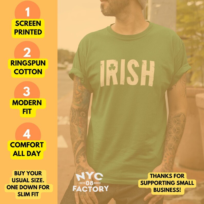 Pode incluir: Camiseta verde com a palavra "IRISH" impressa em branco com um s&iacute;mbolo de trevo. A camiseta &eacute; feita de algod&atilde;o ringspun e tem um caimento moderno. O texto "NYC FACTORY" est&aacute; impresso na parte inferior esquerda da camiseta.
