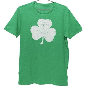 Pode incluir: Uma camiseta verde com um design de trevo branco desbotado.