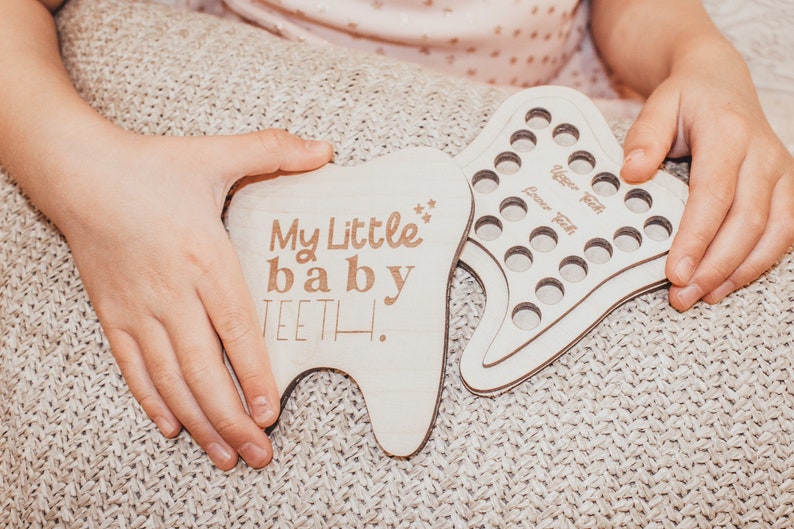 May include: A wooden tooth chart with the text "My Little baby TEETH!" and a separate wooden tooth chart with 20 circles for recording lost baby teeth.
