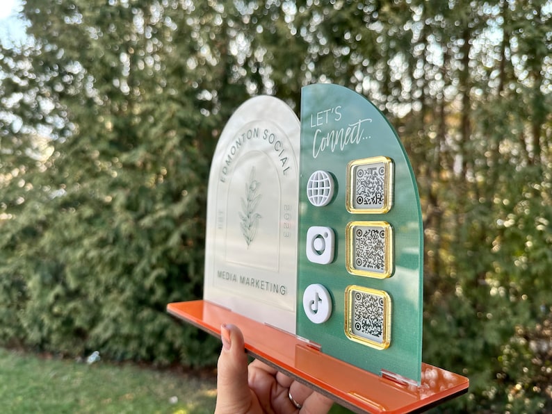 Peut inclure: Une r&eacute;compense en acrylique blanche et verte avec le texte "Edmonton Social Media Marketing" et un motif de plante. La r&eacute;compense comporte une section verte avec le texte "Let's Connect..." et trois codes QR avec des ic&ocirc;nes pour Instagram, TikTok et un globe.