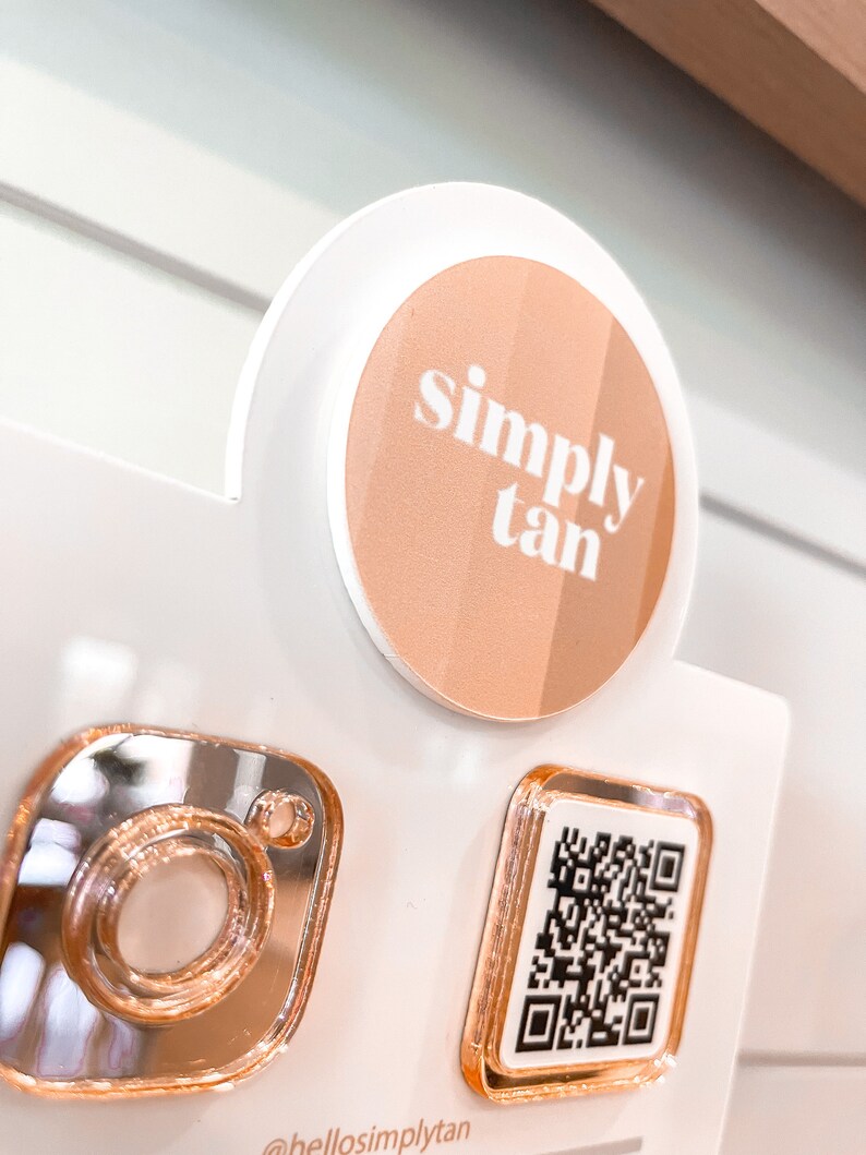 May include: A white and rose gold round sticker with the text "simply tan" in white. A rose gold Instagram icon and a rose gold QR code are also visible.