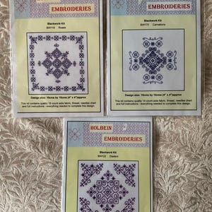 May include: Three Holbein Embroideries blackwork kits. Each kit features a detailed cross-stitch design in dark blue on white aida fabric. The kits include fabric, thread, needles, and instructions. The designs measure approximately 10cm x 10cm and 7cm x 7cm.