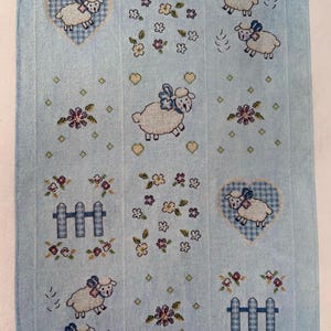 Counted cross stitch baby blanket/afghan kit on soft blue evenweave fabric with sheep and hearts design. 36” x 24.5” finished size.