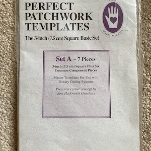 Peut inclure: Un emballage blanc avec une étiquette de produit pour "Perfect Patchwork Templates" de Marti Michell. L'étiquette présente une main avec un logo en forme de cœur et le texte "Set A - 7 Pieces". L'étiquette comprend également le texte "3 pouces (7,5 cm) Square Plus Six Common Component Pieces" et "Master Templates For Use with Rotary Cutting Systems". L'étiquette comprend également le texte "Precision corner concept by Jane Hackworth Gruchacz". Le numéro de produit est 8251.