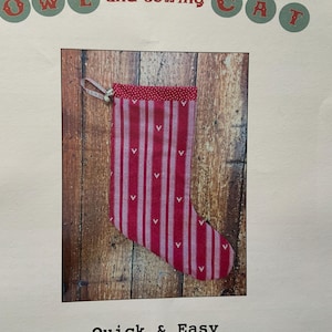 May include: A red and white striped stocking with a pink heart pattern. The stocking has a loop at the top for hanging. Quick & Easy is written below the stocking.