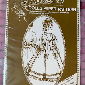 May include: A vintage doll paper pattern package. The package features a detailed illustration of a high-necked day dress with a trained skirt, jacket, hat, and skirt. The package is labelled "NICOLA DOLLS PAPER PATTERN" and includes text about the pattern's fit.