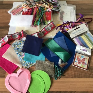 May include: A craft kit with a variety of materials, including fabric, ribbon, thread, and felt. The kit includes a variety of colors, including red, green, blue, and pink. The kit also includes a small package of ribbon labeled "Back to Basics IV".