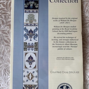 Pode incluir: Um kit de ponto cruz contado da coleção V&A Museum com um design de tapeçaria vertical com padrões florais e geométricos em azul, branco e dourado inspirados em William De Morgan. A embalagem inclui texto histórico e a marca DMC.