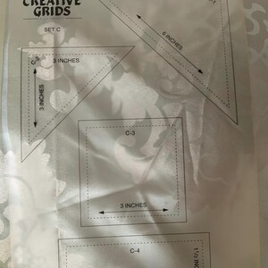以下が含まれることがあります： 半透明の背景に4つの形状の黒い輪郭が描かれたCreative Grids Set Cテンプレートシート。形状には、C-1とラベル付けされた15.24cmの三角形、C-2とラベル付けされた7.62cmの三角形、C-3とラベル付けされた7.62cmの正方形、およびC-4とラベル付けされた11.43cm x 3.81cmの長方形が含まれています。