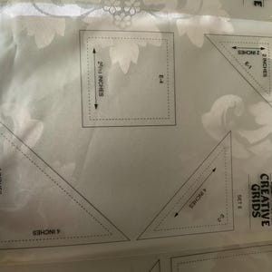 以下が含まれることがあります： 「Creative Grids Set E」とラベル付けされた透明なプラスチック製のキルティングテンプレートシート。2インチ、3インチ、4インチなどのインチ単位の測定値が印刷された三角形や正方形などのさまざまな幾何学模様が、白い背景の上に配置されています。