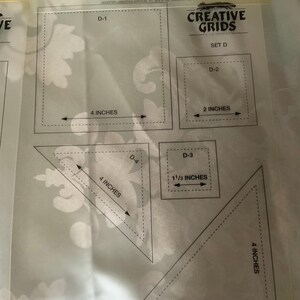 以下が含まれることがあります： インチ単位の寸法が印刷されたCreative Grids Set Dの透明なプラスチック製キルティングテンプレートシート。D-1からD-5までのラベルが付いた様々な形状が含まれており、4インチの長方形、2インチの正方形、1 1/3インチの正方形、および2つの4インチの三角形で構成されています。
