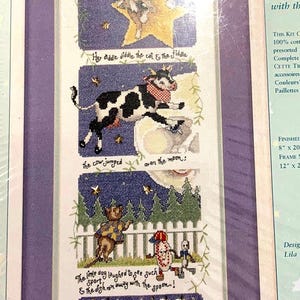 May include: Cross-stitch kit featuring a nursery rhyme scene with a cat and a fiddle, a cow jumping over the moon, and a dog laughing. The text includes the phrases "Hey diddle diddle" and "The dish ran away with the spoon!"