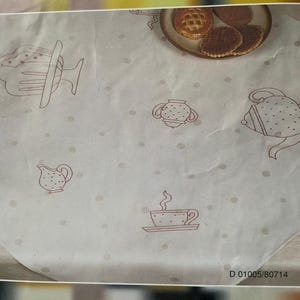 May include: A white tablecloth featuring a repeating brown line-art pattern of teapots, teacups, sugar bowls, and creamers, accented with small brown polka dots. A plate with three round cookies is visible in the upper right corner. Text D 01005/80714.