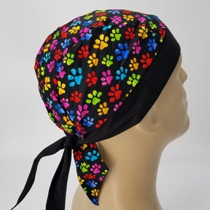 May include: A black bandana with a colorful paw print pattern. The bandana is tied on a mannequin's head.