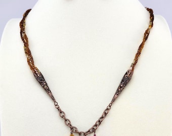 May include: A necklace and earring set featuring a multi-strand beaded necklace with a copper-colored chain and accents. The necklace has dangling brown and amber-colored beads. The earrings have matching brown and amber beads.