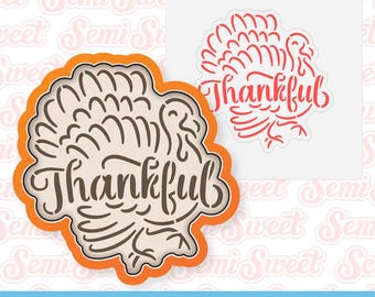 May include: A cookie cutter and stencil bundle featuring a turkey design with the word "Thankful". The cookie cutter is outlined in orange, while the stencil is red. The text "Cookie Cutter & Stencil Bundle" is at the bottom.