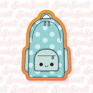 May include: A blue and white polka dot backpack cookie cutter with a smiling face and a zipper detail.