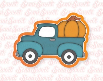 May include: A teal blue vintage pickup truck with an orange pumpkin in the bed. The truck has black wheels and a white interior. The pumpkin has a brown stem.