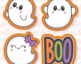 May include: A set of four orange-rimmed cookie cutters featuring three white ghost shapes with smiling faces and pink cheeks, one of which wears a purple bow, and a fourth cutter shaped like the word BOO in orange, green, and purple letters.