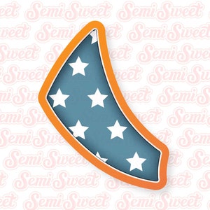 May include: A cookie cutter shaped like a crescent moon with a blue and white star pattern. The cutter is outlined in orange.
