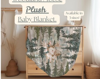 Puede incluir: Una manta de bebé suave y de felpa con un alce de bosque con un pájaro en sus astas. La manta tiene un diseño de estilo acuarela de árboles y un fondo azul claro. El texto "Woodland Moose Plush Baby Blanket" y "Available in 3 sizes!" se muestra en la imagen.