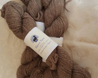 Puede incluir: Madeja de hilo de alpaca marrón con una etiqueta que dice "Alpaca Yarn". El hilo es de color marrón natural y parece suave y texturizado. La etiqueta también menciona "Davidson Estate Alpacas".
